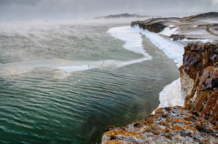 Baikal Lake and rock in the December cold. Time of freeze-up. Ice floes is swiming on the waterの写真素材