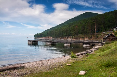 Idyllic view of the wooden pier in the lake with mountain scenery background. Lake Baikal in the...