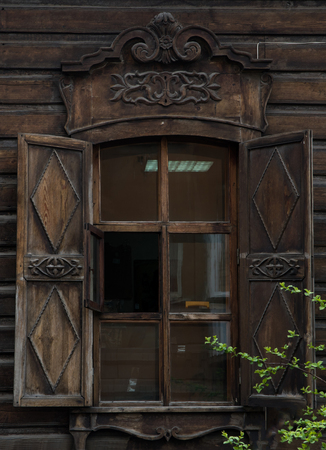 The window with the wooden carved architrave in the old wooden house in the old Russian town.の写真素材
