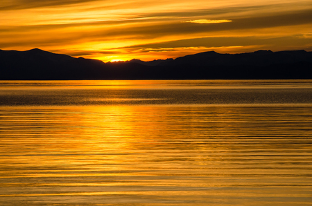 Beautiful gold and orange sunset above the sea and mountainの写真素材