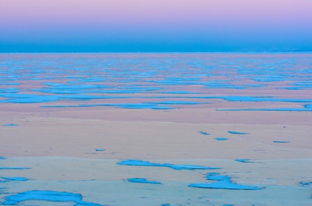 Blue ice of Baikal lake under pink sunset sky. Background