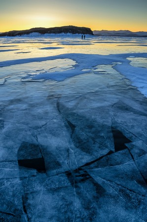 View of beautiful drawings on ice from cracks and bubbles of deep gas on surface of Baikal lake in winter with mountain, Russiaの写真素材