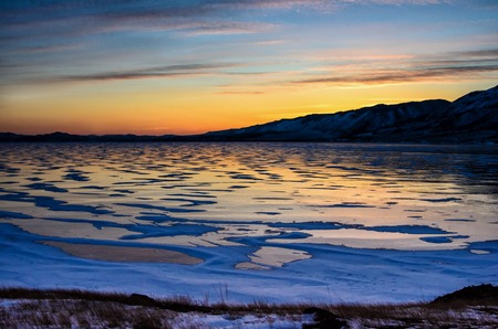Amazimg orange view of the ice and the rising sun over the mountains, lake Baikalの写真素材