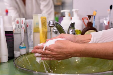 Woman use soap and washing hands under the water tap. Hygiene concept hand detail.の写真素材