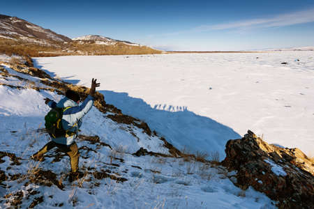 Lake Baikal, Russia - March 8, 2020: Man view from back shows the figure and the bottom turns out to be funny shadowy silhouettes. Frozen lake Baikal covered with snow.のeditorial素材