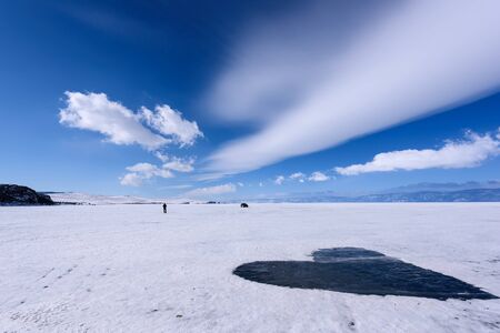 Frozen Lake Baikal covered with snow and cleared of snow in shape of heart. Beautiful stratus clouds...