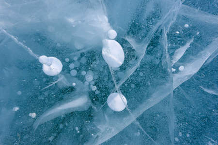 Beautiful ice of Lake Baikal with abstract cracks and frozen air bubbles
