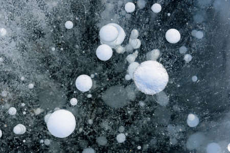 Beautiful ice of Lake Baikal with abstract cracks and frozen air bubbles