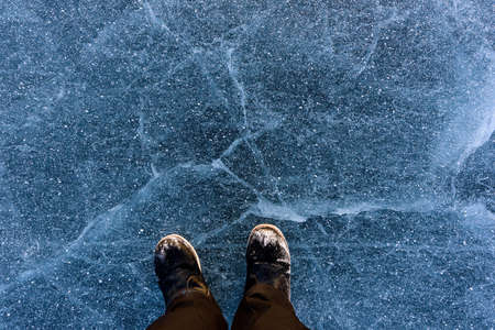 Beautiful ice of Lake Baikal with abstract cracks with shoes. Top viewの写真素材
