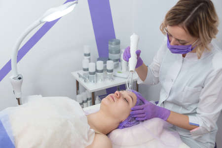 Beauty salon. The cosmetologist makes a water peeling procedure for the client. Side view. The concept of professional skin care.の写真素材