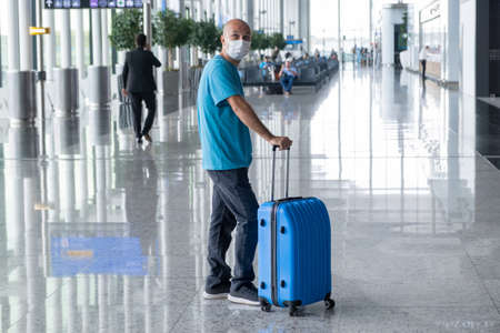 ISTANBUL, TURKEY - September 7, 2021: Man pulling suitcase in Istanbul airport terminal and looked around. Travelling guy wearing casual clothes and mask. Copy spaceのeditorial素材