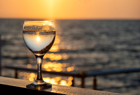 Glass of white wine at sunset near seaside with copy spaceの写真素材