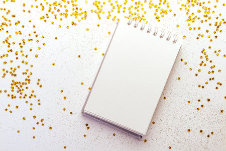 White notebook with spring lies on white background with gold stars glittersの写真素材