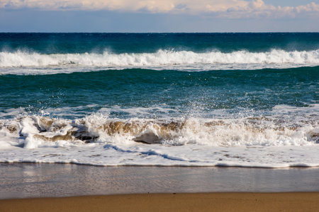 Sea wave breaks on sandy beach with clouds sky on Mediterranean coast of Mersin province, Atakent
