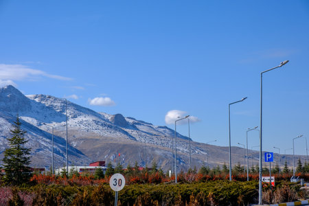 Rural landscape with snow-covered hills, fir trees, blue sky