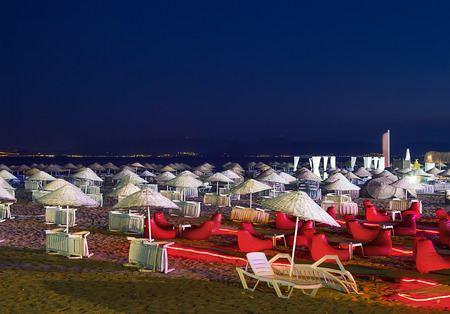 Beds and straw umbrellas on Sarimsakli Beach, Turkey At Nightの写真素材