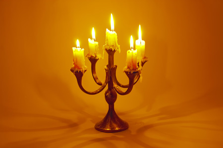 old candlestick with burning candles on a red backgroundの写真素材