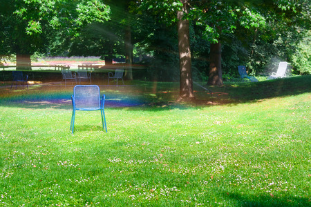 Chaise lounge for relaxing on a green meadow.Watering the lawn in the city park.の写真素材