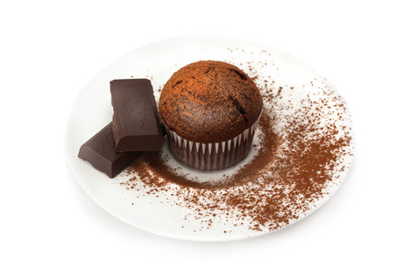 Chocolate muffin on a saucer in the cocoa powder isolated on a whiteの写真素材