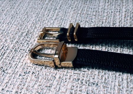 black leather belt with golden buckle on a gray textured backgroundの写真素材