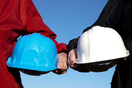 two hard-hats (blue and white color) focus on hand of manの写真素材