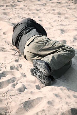 homeless man sleeping on sandの写真素材