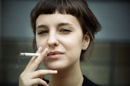 young female with cigarette, selective focus on eyes, toned photo f/xの写真素材