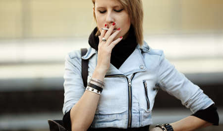 real young woman smokes on the street, natural light, selective focusの写真素材