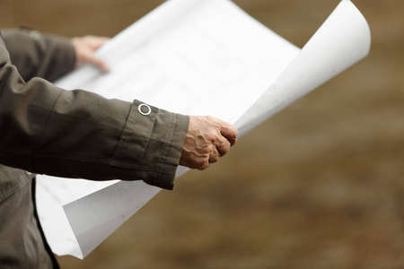 inspector with construction plan, natural light, selective focus on nearest part of handの写真素材
