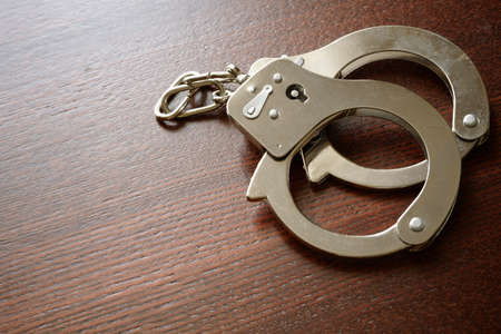 handcuffs on the wooden desk, crime concept の写真素材