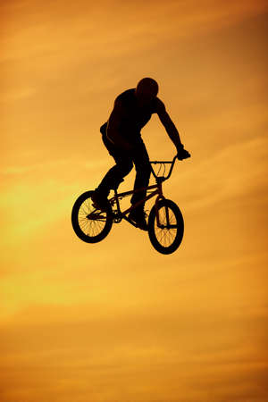 bmx jump on bright orange sky backgroundの写真素材