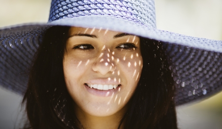 Happy smiling girl wearing a blue hat on the sea beachの写真素材