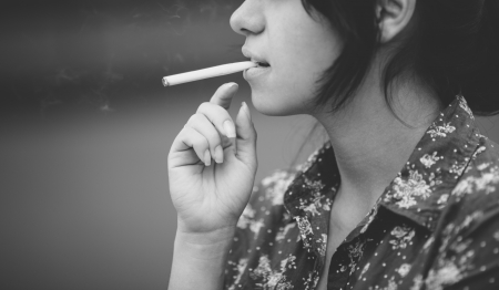 real young woman smokes on the street, selective focusの写真素材
