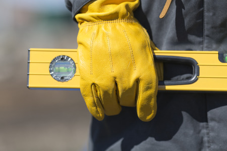 hand of worker with yellow glove and levelの写真素材