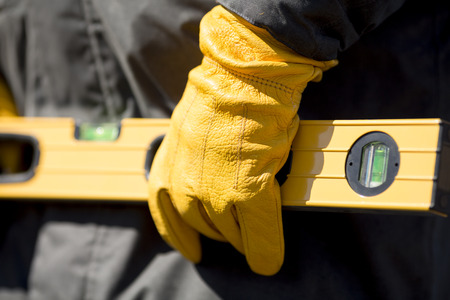 hand of worker with yellow glove and levelの写真素材