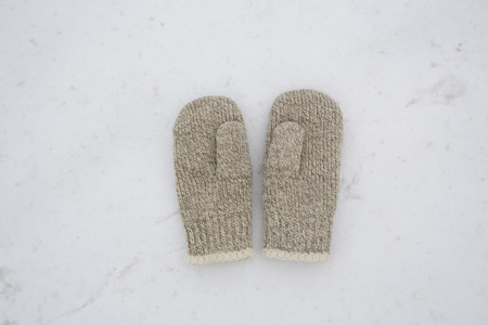couple of wool mittens on the white snow backgroundの写真素材