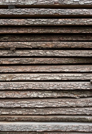 Folded wooden brown and gray planks in a sawmill. Piled alder boards as texture for design.