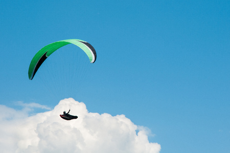 Alone paraglider flying in the blue sky against the background of clouds. Paragliding in the sky on a sunny day.の写真素材