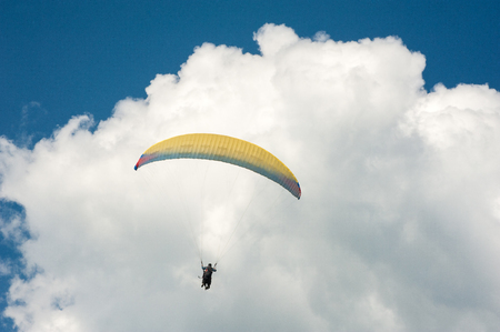 Alone paraglider flying in the blue sky against the background of clouds. Paragliding in the sky on...