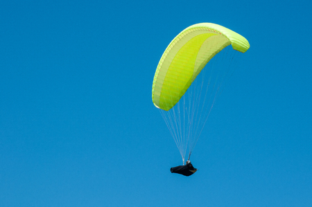Alone paraglider flying on the background of blue sky. Paragliding in the sky on a sunny day.の写真素材