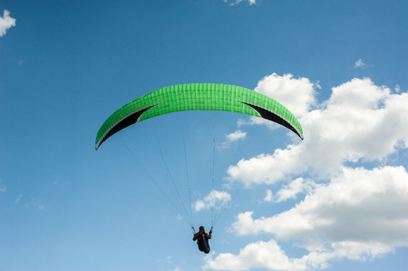 Paraglider flying in the blue sky against the background of clouds. Paragliding in the sky on a sunny day.のeditorial素材