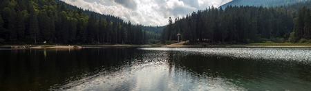 Beautiful views of the mountain lake and the mountains covered with forest in the summer. Popular tourist attraction. Fantastic landscape of Lake Sinevir in the Carpathians, Ukraine.の写真素材