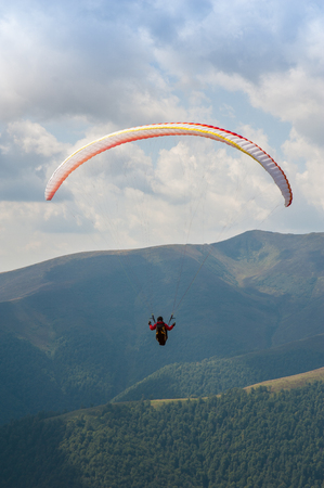 One paraglider fly over a mountain valley on a sunny summer day. Paragliding in the Carpathians in the summer.の写真素材