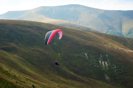 Paraglider fly over a mountain valley on a sunny summer day. Paragliding in the Carpathians in the summer.の写真素材