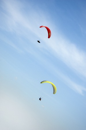 Two paragliders flying in the blue sky against the background of clouds. Paragliding in the sky on a...