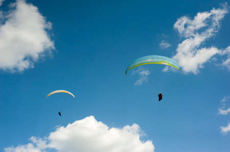 Two paragliders flying in the blue sky against the background of clouds. Paragliding in the sky on a sunny day.の写真素材