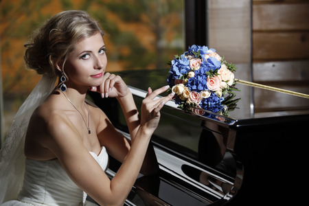 Bride with a bouquet sits at the pianoの写真素材