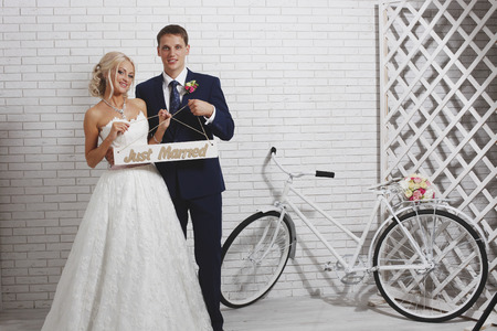 The bride and groom and the bike at a brick wallの写真素材