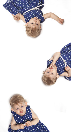Little baby girl in blue dress lying on white backgroundの写真素材
