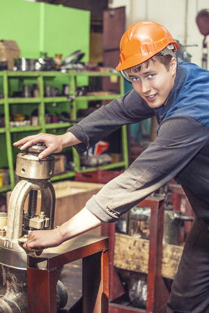 The young man working at the old factory on installation of equipment in a protective helmet